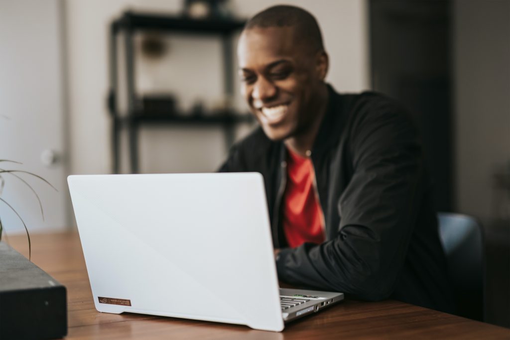 Man in black jacket smiling at a laptop