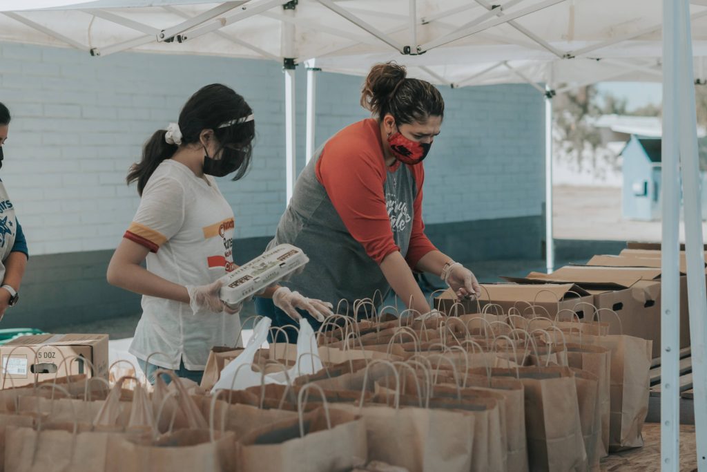 Two volunteers preparing food donation bags